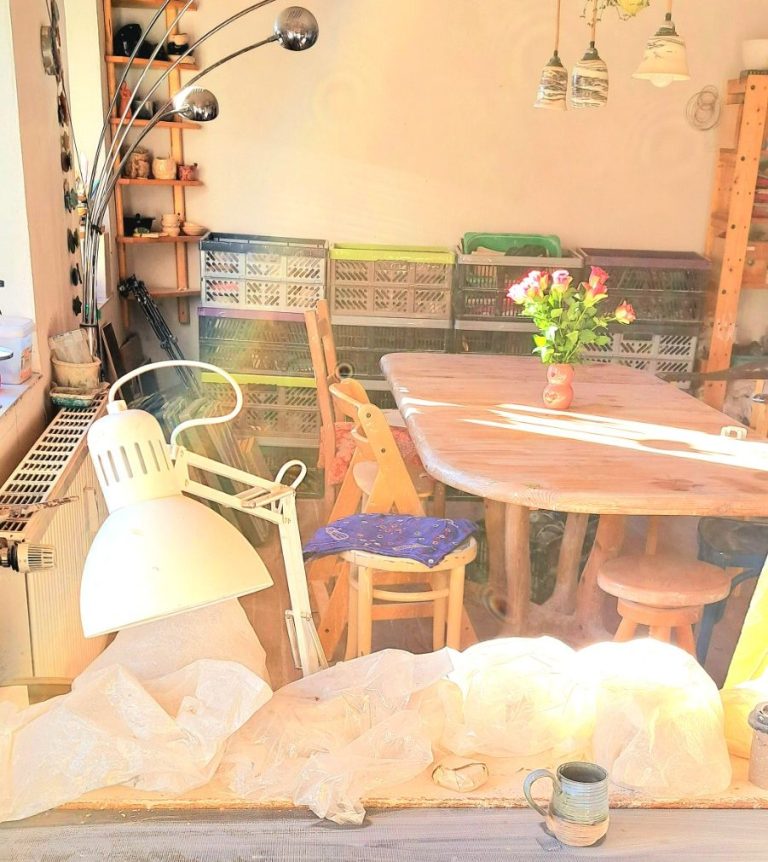 Töpferei mieten Arbeitsbereich mit Lampen, Tischen und Tontöpfen, umgeben von weißem Material.