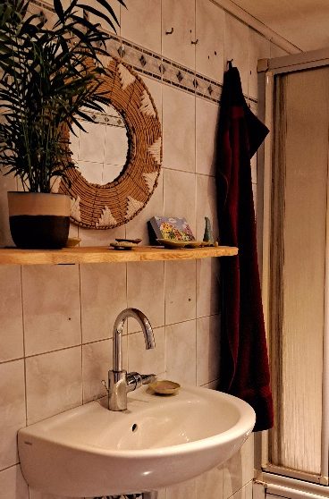 Töpferei mieten Ein helles Zimmer mit einem Holztisch, Vasen mit Blumen und Regalen im Hintergrund.